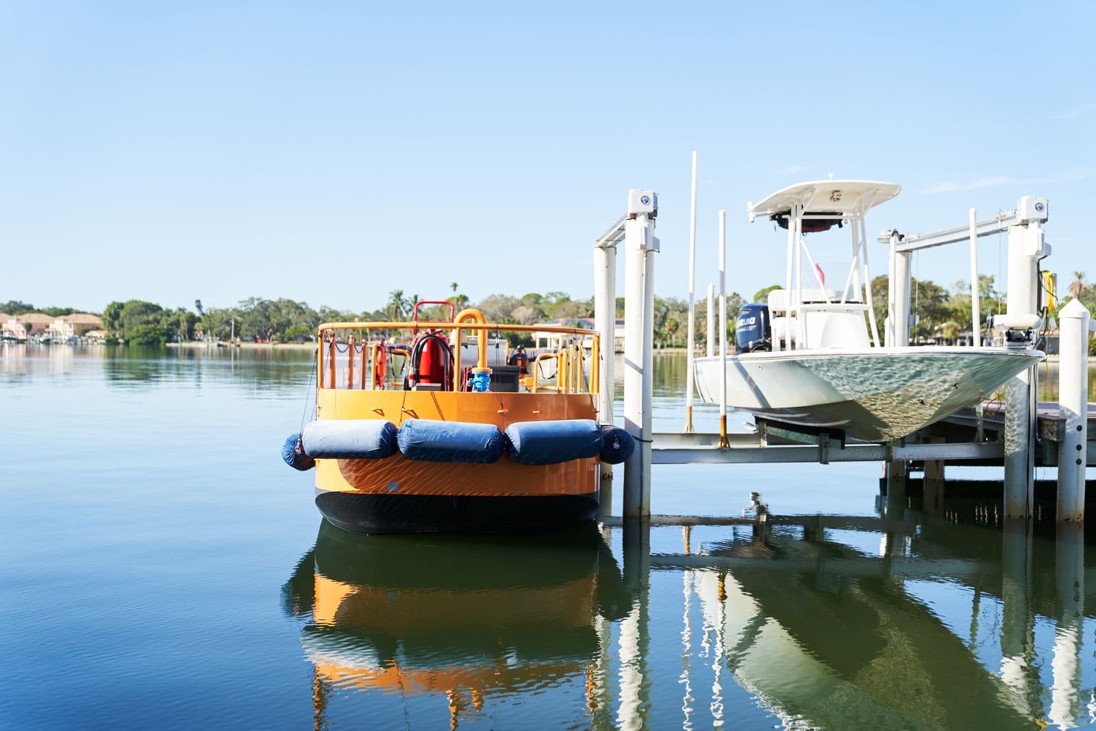 Mobile Marina fuel vessel reflected in calm water beside boats at dock