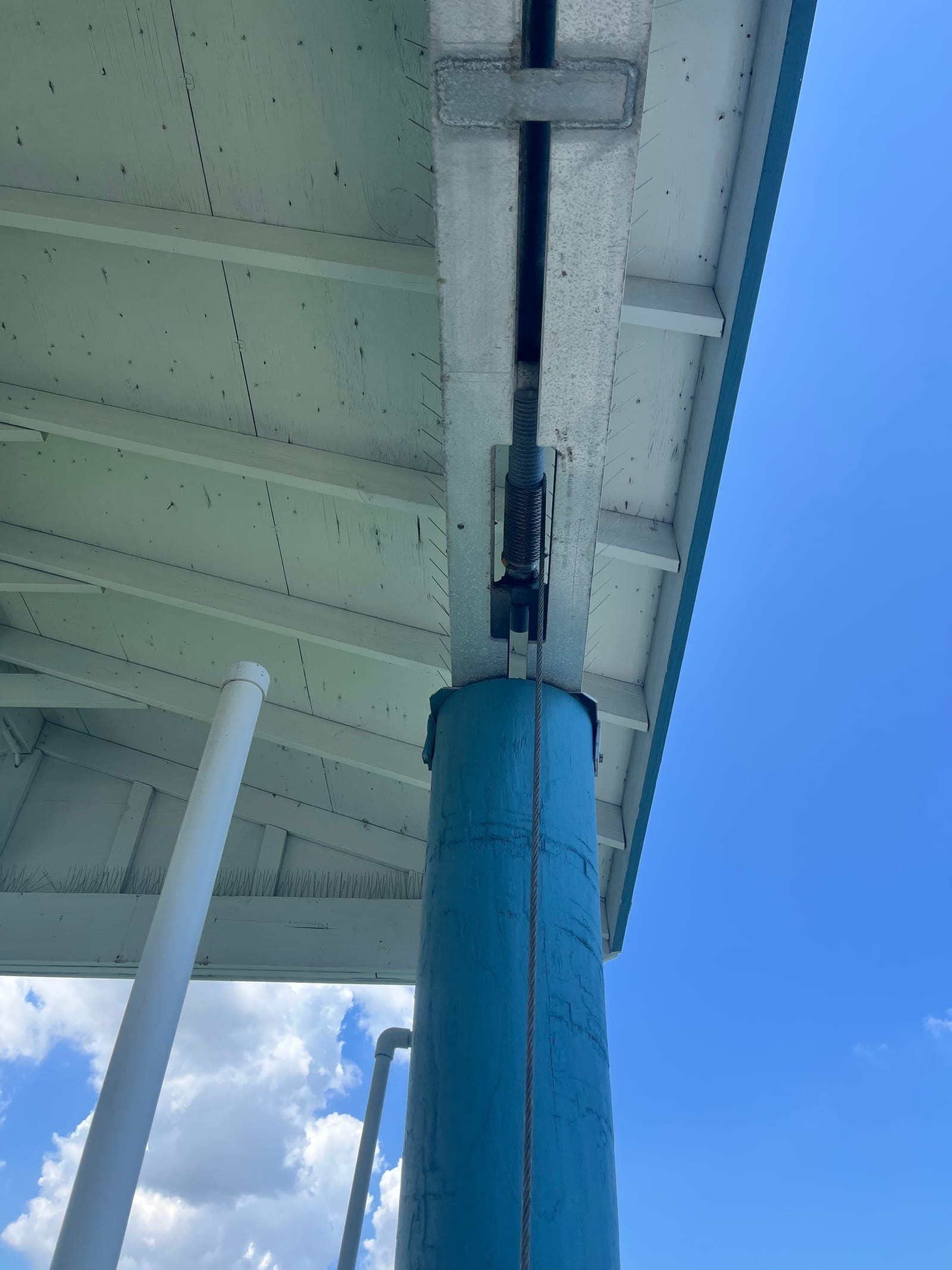 Cable, wrap assembly, and guide bracket above a blue piling on a personal watercraft lift in Tampa Bay