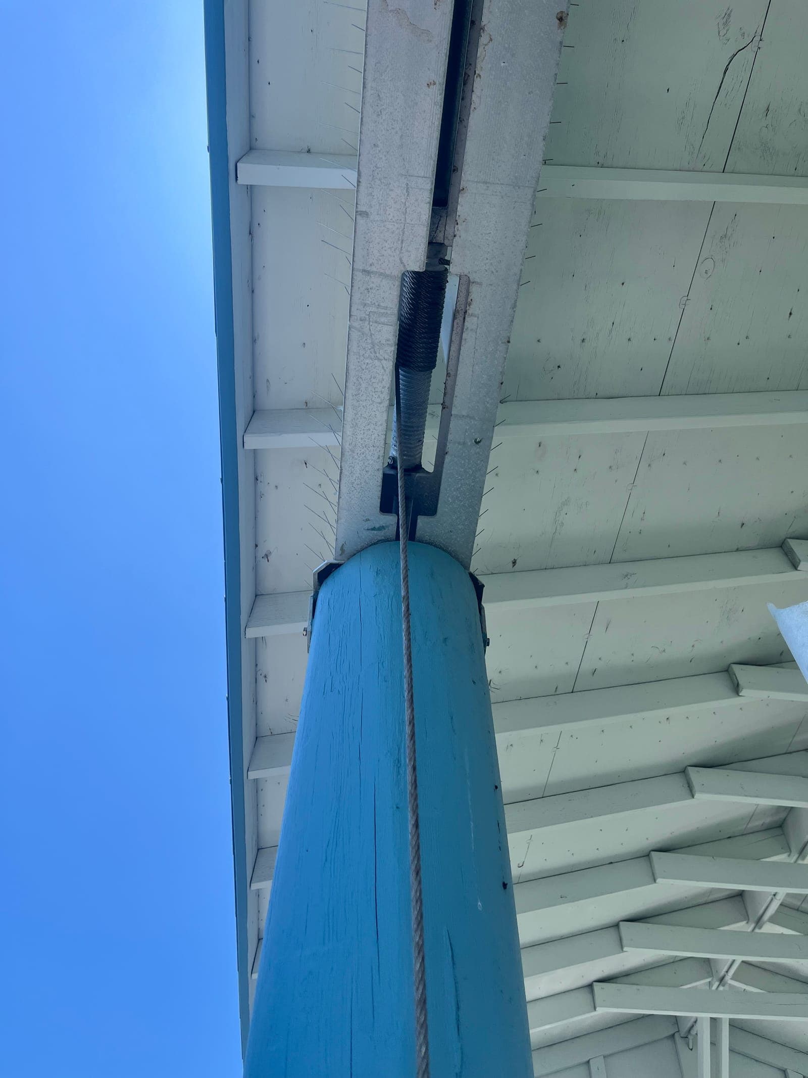 Close view of a boat lift cable wrap assembly and bracket mounted above a piling