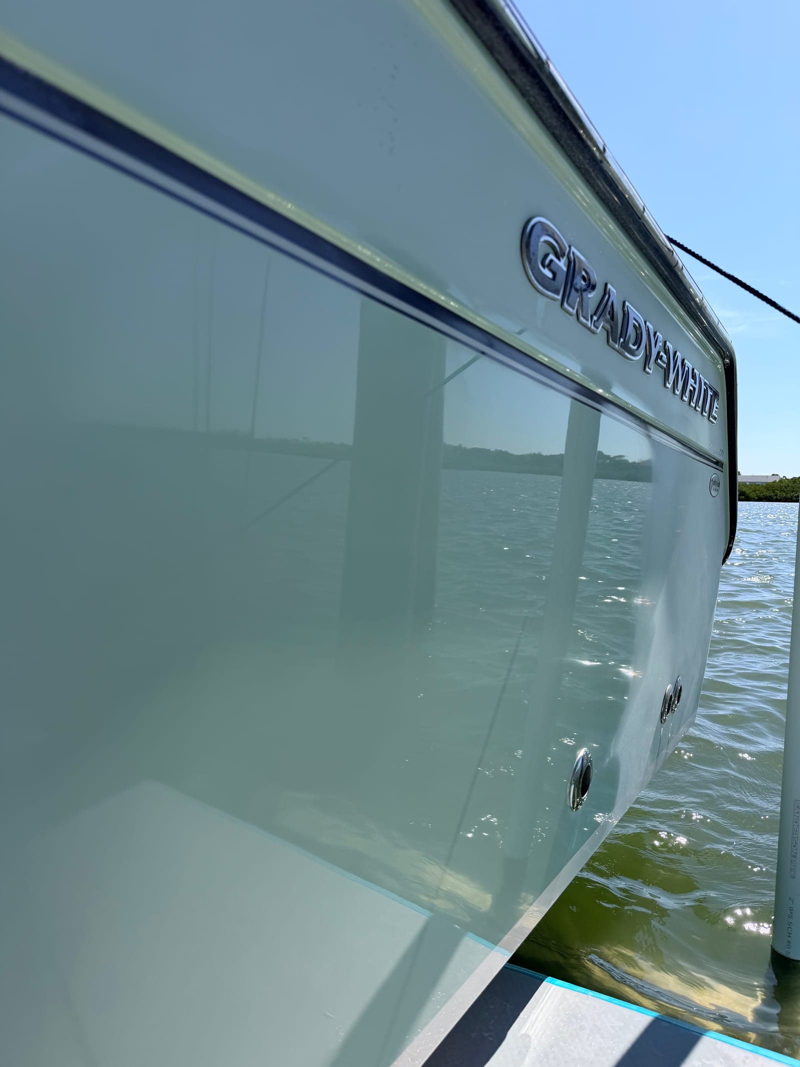 Grady-White hull at a Tampa Bay slip after a full Mobile Marina detail — gelcoat polished to mirror-finish, reflecting sky and water