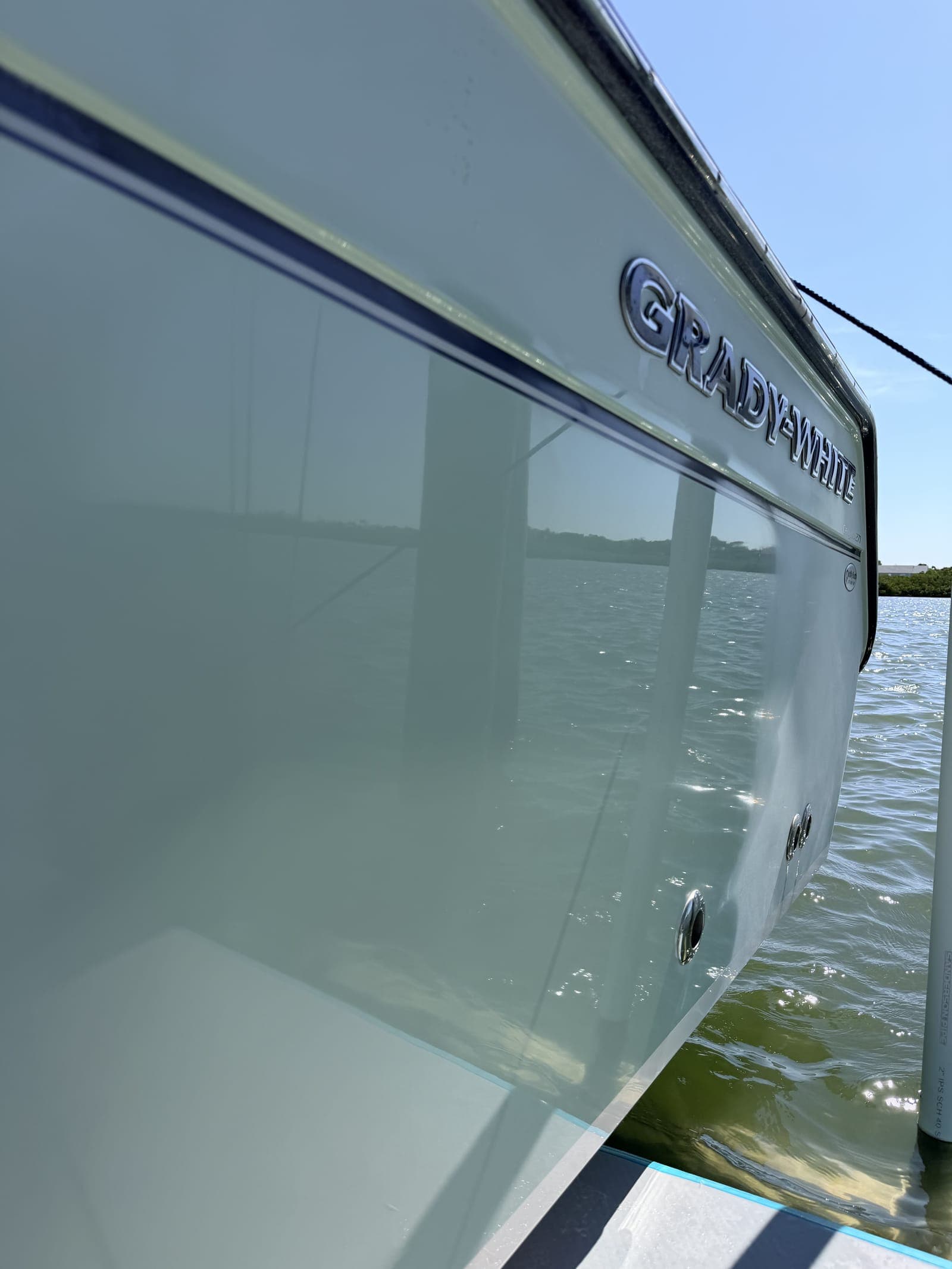 Polished Grady-White hull at a Tampa Bay slip — a smooth, reflective gelcoat sidewall is what passes the basic-wash test. Anything dull or gritty signals you need a step beyond a wash.