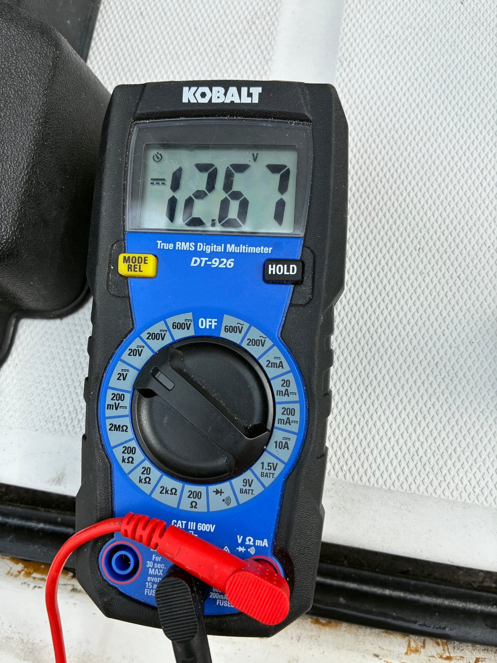 Multimeter voltage check on a Mercury outboard's charging system during a scheduled service