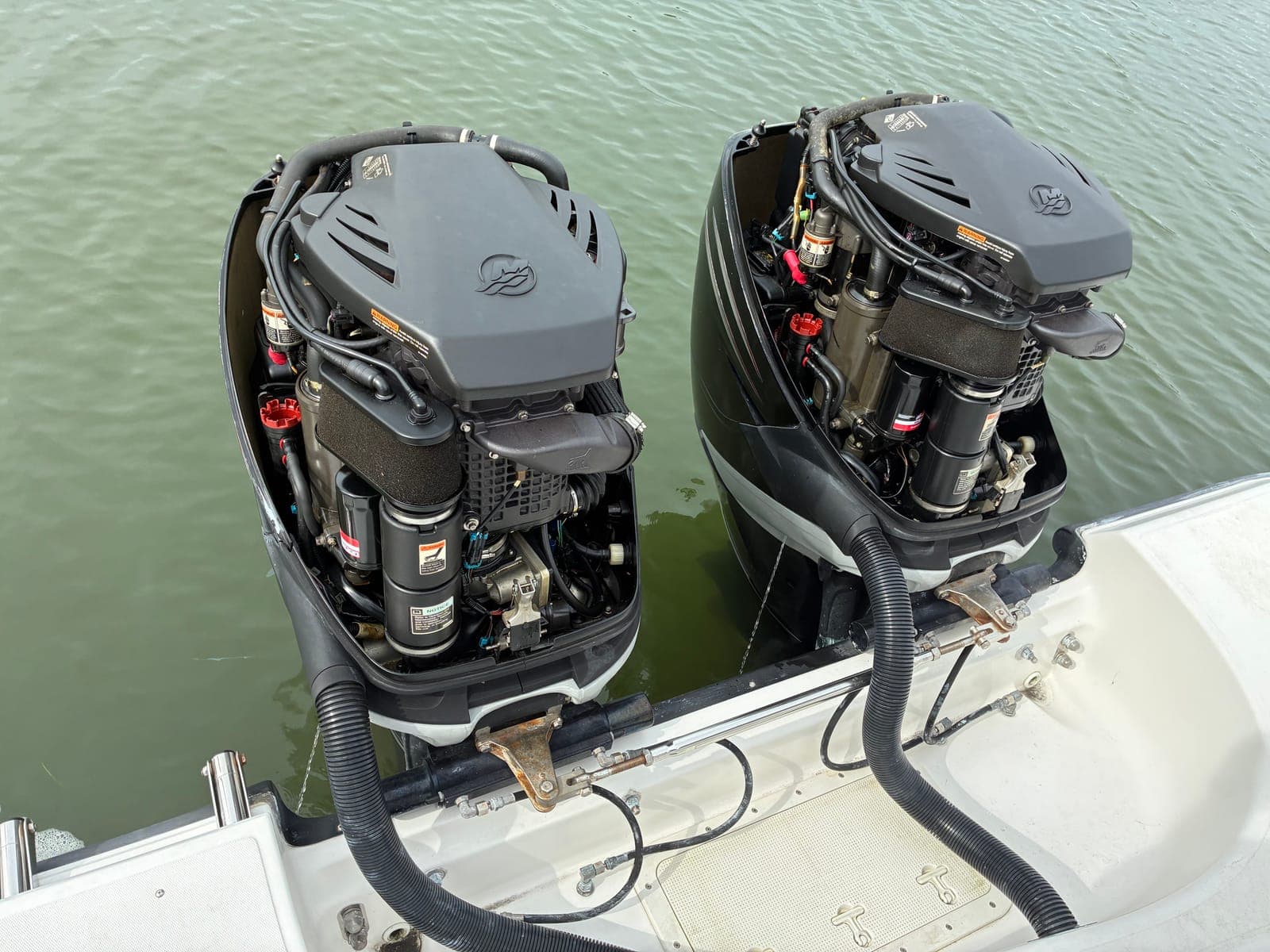 Twin Mercury outboards with cowlings removed during a dockside service visit in Tampa Bay