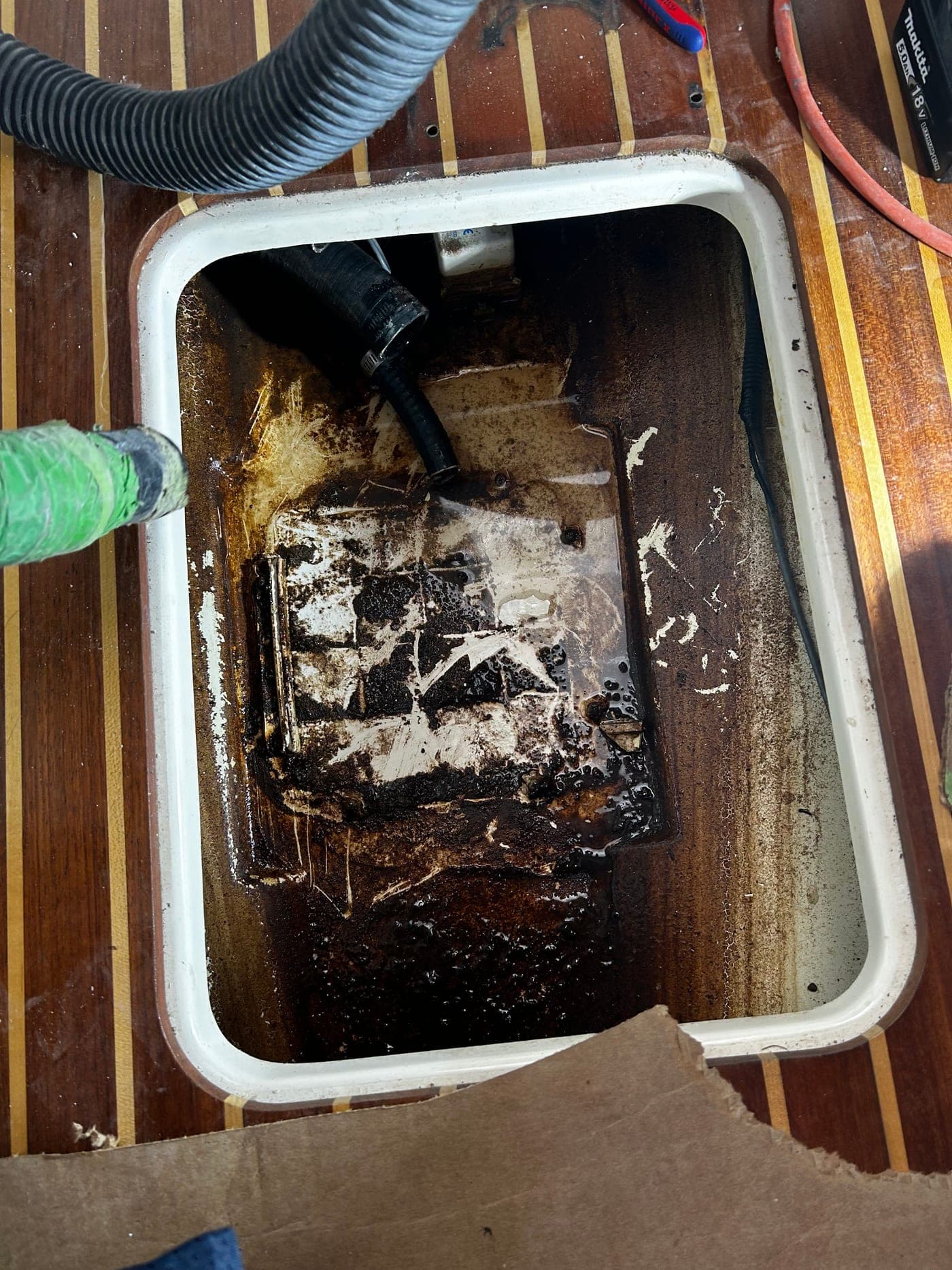 Open center fuel tank compartment on a Boston Whaler 305 during removal, with residual contamination and disconnected hoses visible