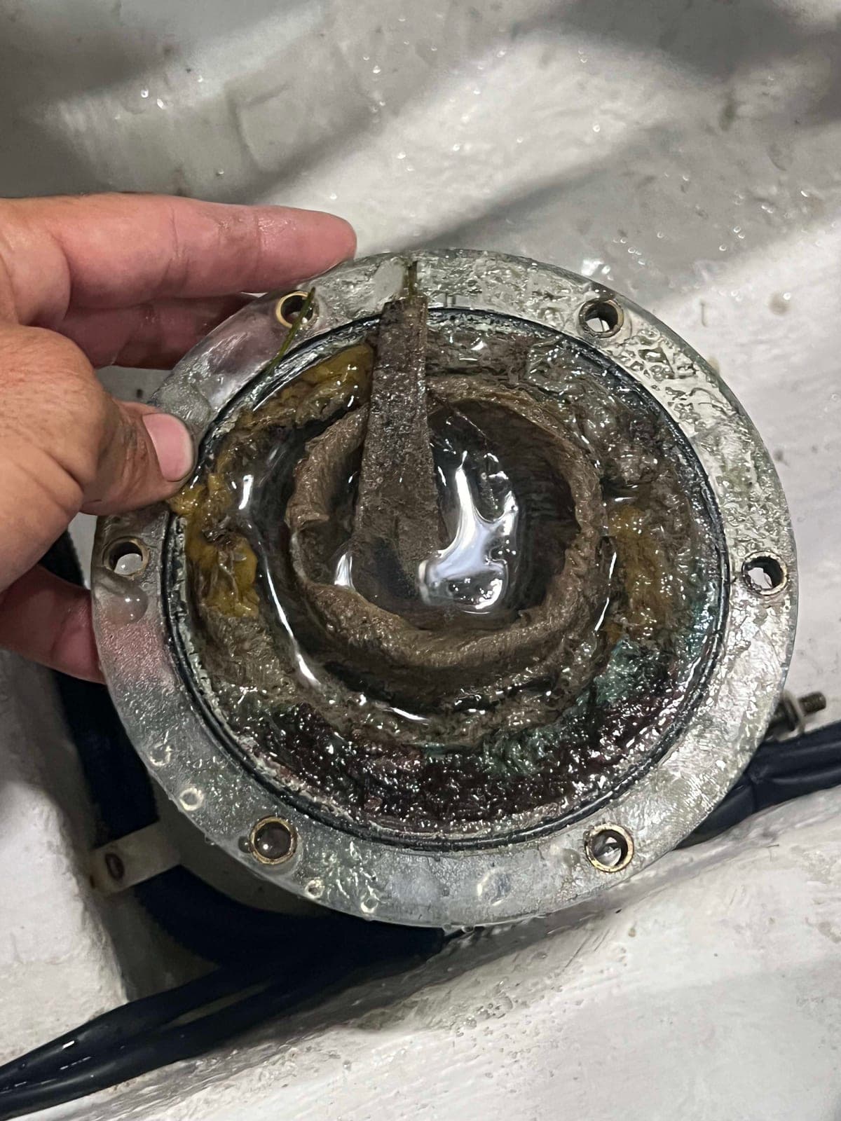 Open marine air-conditioning seawater strainer housing packed with heavy organic growth and debris